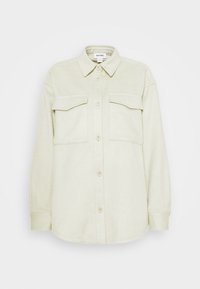 Camicia in flanella verde chiaro con colletto, chiusura frontale con bottoni, due tasche sul petto e maniche lunghe. Texture morbida e vestibilità rilassata.