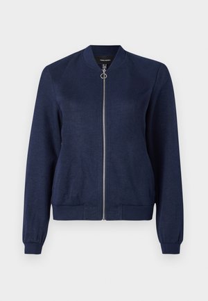 Marineblå bomberjakke med sølvglidelås og rund trekk, med ribbede mansjetter og linning, mot en ensfarget hvit bakgrunn.