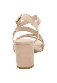 Beige högklackad sandal med tjock klossklack, remdesign och en slät textur. Justerbar ankelsnörning för passform.