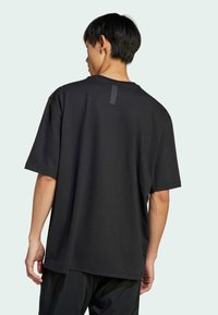 Black short-sleeve t-shirt with a crew neck and a subtle logo detail on the back. Made of smooth fabric with a relaxed fit.