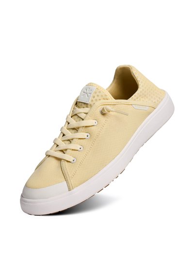 Baskets basses jaune clair avec semelle blanche, tissu en mesh, lacets à l'avant et col rembourré, vues en angle latéral.