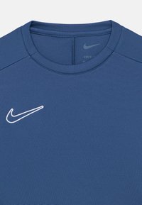 Μπλε αθλητική μπλούζα με λαιμόκοψη round neck, κατασκευασμένη από υφασμάτινη υφή. Διαθέτει λευκό λογότυπο Nike στην αριστερή πλευρά του στήθους.