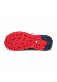 Suela de zapato de goma roja y azul marino con lengüetas de tracción multidireccional pronunciadas y un acento central blanco para mayor agarre y durabilidad.