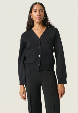 Zwarte gebreide cardigan met een V-hals, knopen aan de voorkant, twee opgestikte zakken en geribbelde manchetten. Soepele textuur, kort model.