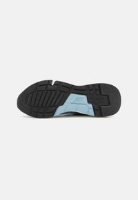 Schwarze Außensohle mit strukturiertem Profilmuster und einem blauen Abschnitt; ausgestattet mit Branding und ausgeprägten Rillen für besseren Halt.