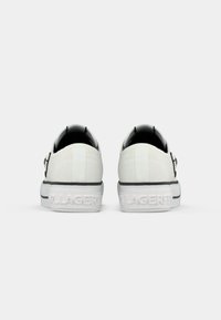 Een paar witte lage sneakers gezien vanuit de achterkant, met dikke zolen waarop gedeeltelijke "Karl Lagerfeld" branding is gedrukt.