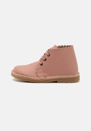 Stivali alla caviglia in pelle rosa con colletto ondulato, punta rotonda e suola piatta in gomma; dotati di lacci marroni e dettagli di cucitura decorativa.