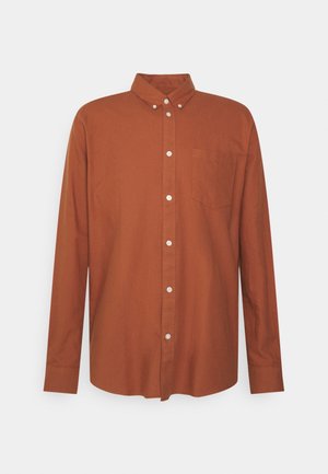 Koszula z długim rękawem na guziki w bogatym brązowym kolorze z bawełny, z klasycznym kołnierzem, przednią kieszenią i białymi guzikami dla kontrastu na listwie.