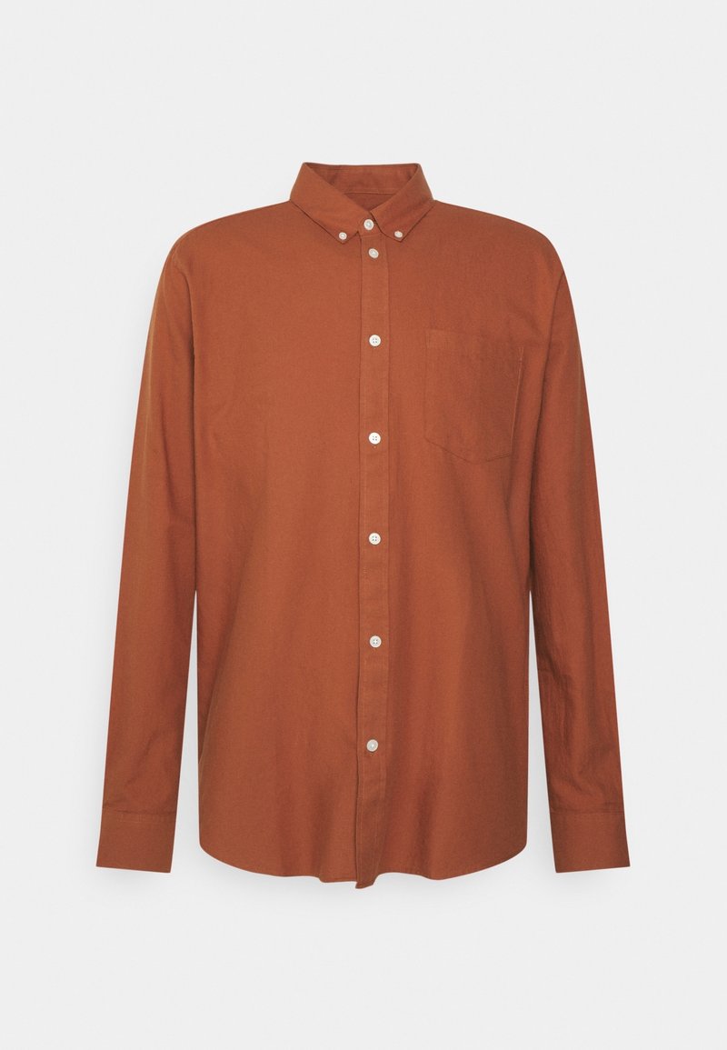 Chemise à manches longues, boutonnée, en coton brun riche, avec un col classique, une poche avant et des boutons blancs contrastant sur la patte de boutonnage.