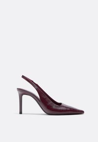 Burgundy leather slingback heels with a pointed toe, slim stiletto heel, and textured finish. Open heel and side for airflow.