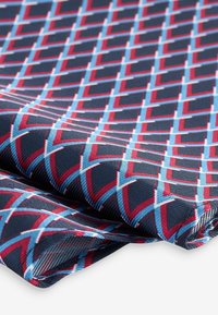 Navy fabric with a geometric pattern of red and light blue diamond shapes. Smooth texture with a slight sheen, folded at the edges.