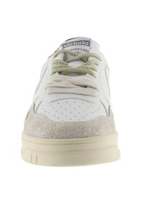 Vit sneaker med texturerad mockadetalj, gräddfärgad sula och blandade snören i ljusgrön och beige. Perforerad tå för luftgenomsläpp.