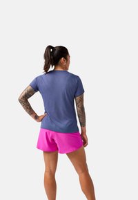 Camiseta deportiva de color azul marino combinada con pantalones cortos de color rosa brillante. La camiseta tiene mangas cortas; los pantalones cortos son de largo por encima de la rodilla con un acabado suave.