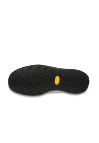 Semelle de chaussure en caoutchouc noir avec un motif de rainure en zigzag texturé et un logo en caoutchouc jaune prominent près du centre.