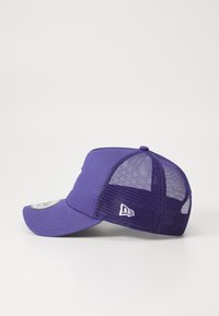 Lilla baseballcap med en struktureret front og mesh-sider, med en buet skygge og et hvidt logo på siden.