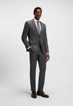 Grey two-piece suit with notched lapels, a light pink shirt, and a textured green tie. Brown dress shoes complete the look.