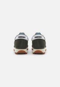 Dark green suede sneakers with white heel accents and black branding. Features a beige midsole and a textured gum rubber outsole.