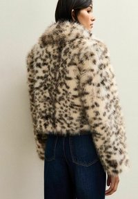 Neppels jacket met een korte, boxy pasvorm. Voornamelijk crème met donkere bruine luipaardvlekken. Beschikt over een brede kraag en volle mouwen.