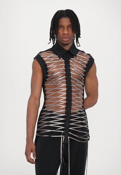 Chemise noire avec un devant transparent, ornée de lacets en ruban argenté entrecroisés dans un motif, design sans manches et col.