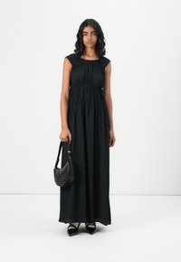 Svart, plisserad maxiklänning med korta ärmar och en veckad byst. Matchad med en texturerad svart handväska med nitar.