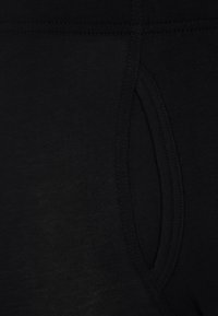 Czarne legginsy sportowe o gładkiej teksturze, z boczną kieszenią i wzmocnionymi szwami dla większej trwałości.