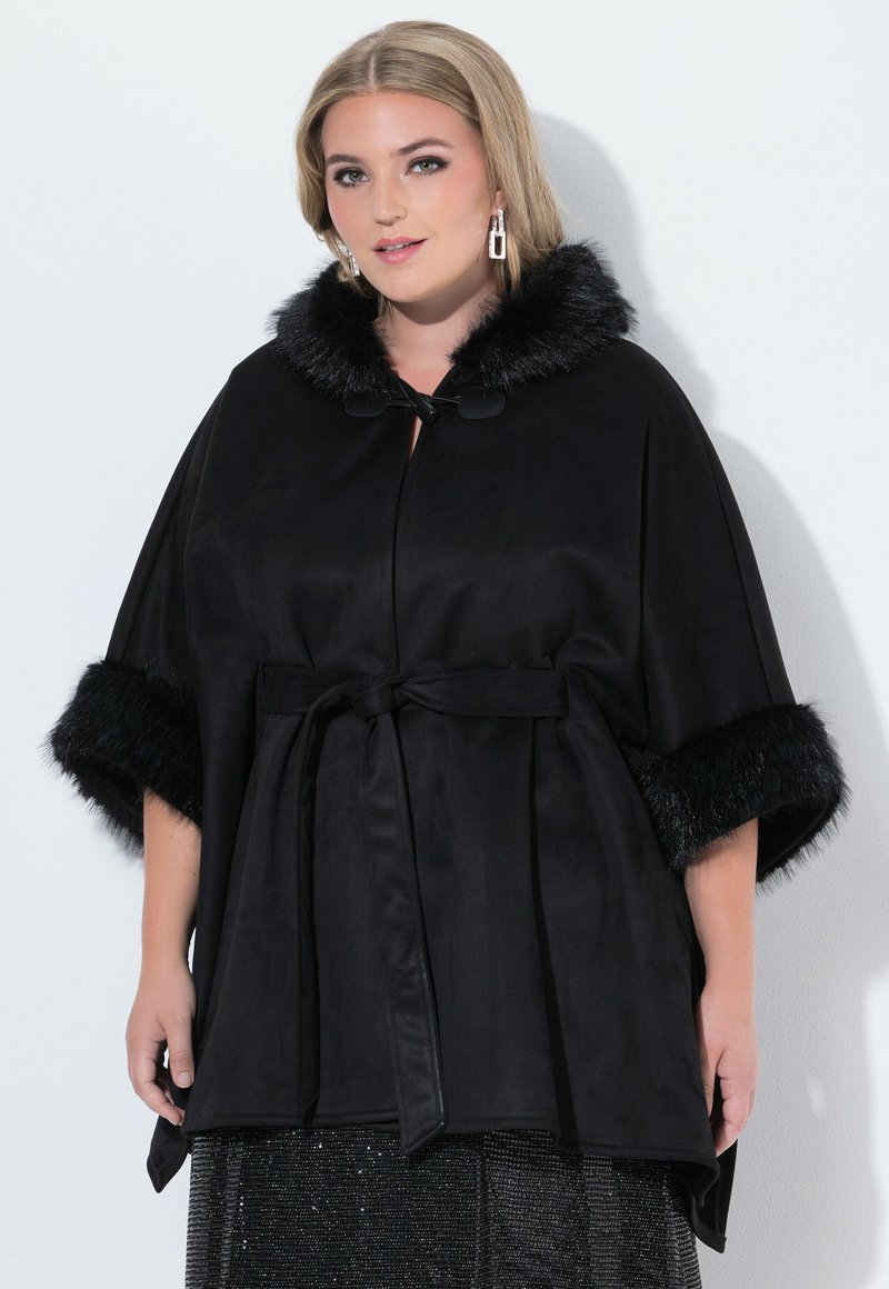 Capa negra con cuello y puños de piel sintética, cinturilla ajustada, textura suave, mangas cortas y un diseño drapeado. Ideal para superponer.