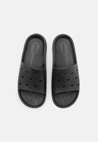 Svarte gummisandaler med flere ventilasjonshull, teksturert fotseng og myk, formet overdel for komfort.