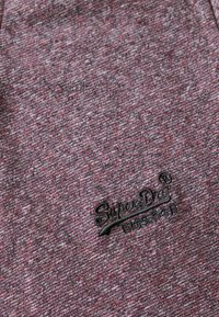 Rood en grijs gemarmerd stoffen t-shirt met zwart geborduurd "SuperDry" logo. Zachte textuur en casual ontwerp met korte mouwen.