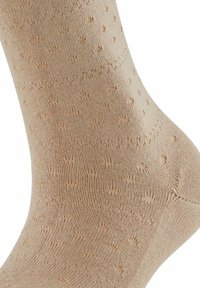 Beżowe skarpetki z prążkowaną teksturą i małymi, wypukłymi kropeczkami na całej powierzchni. Projekt jest bezszwowy na górze dla wygody.
