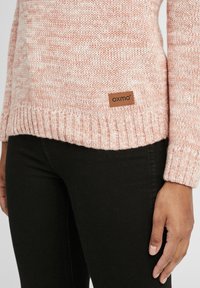 Maglione lavorato a maglia in rosa chiaro e bianco con tessuto testurizzato, dotato di un orlo a coste e di una piccola etichetta in pelle marrone con il marchio "oxmo".