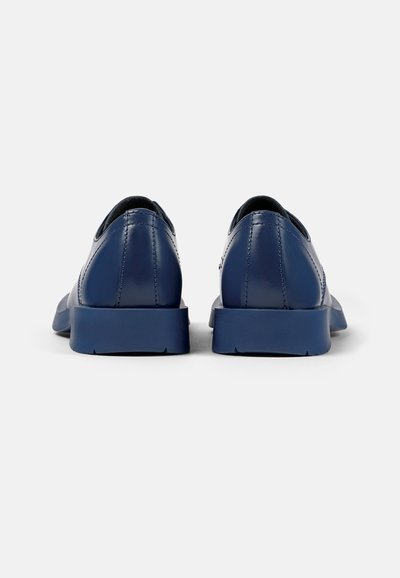 Donkerblauwe leren schoenen met een zachte textuur, een ronde neus en een stevige zool. Bevat subtiele stiksels en heeft een laag uitgesneden ontwerp bij de hak.