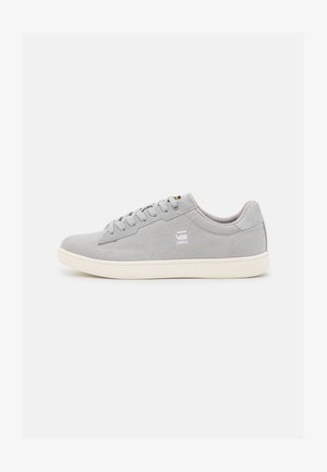 Gray canvas sneakers with a low profile, round toe, and white rubber sole; features lace-up design and branding on the side.
