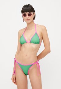 Green mesh bikini with pink trim; triangle top and low-rise bottom with ties. Smooth texture, lightweight design for swimwear.