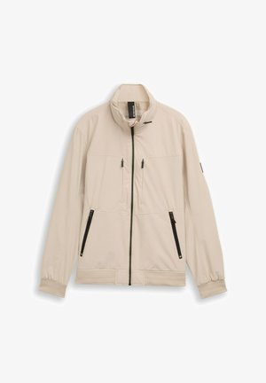 Beige lichtgewicht jack met hoge kraag, ritssluiting aan de voorkant en twee voorzakken met zwarte ritsen. Mouwen met manchetten en een zoombanddetail.