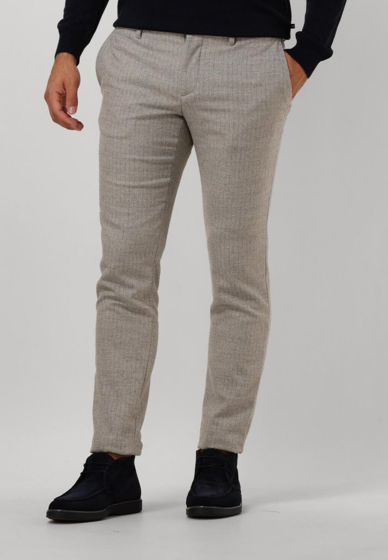 Light beige tailored trousers with a subtle check pattern, made of smooth fabric, featuring a slim fit and pockets. Worn with dark boots.