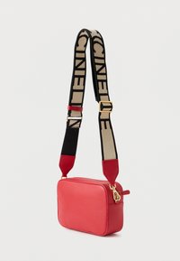 Piros bőr oldaltáska cipzáras záródással, texturált felülettel, mintás fekete és bézs pánttal, arany színű fém kiegészítőkkel.