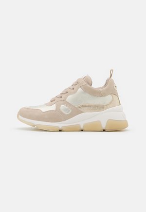 Beige sneaker featuring suede and mesh materials, round toe, lace-up design, and a rubber sole with a textured, light-colored midsole.