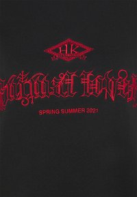 Svart bomulls t-shirt med djärv röd gotisk stil broderi med "HK"-logotyp och texten "SPRING SUMMER 2021". Slät textur.