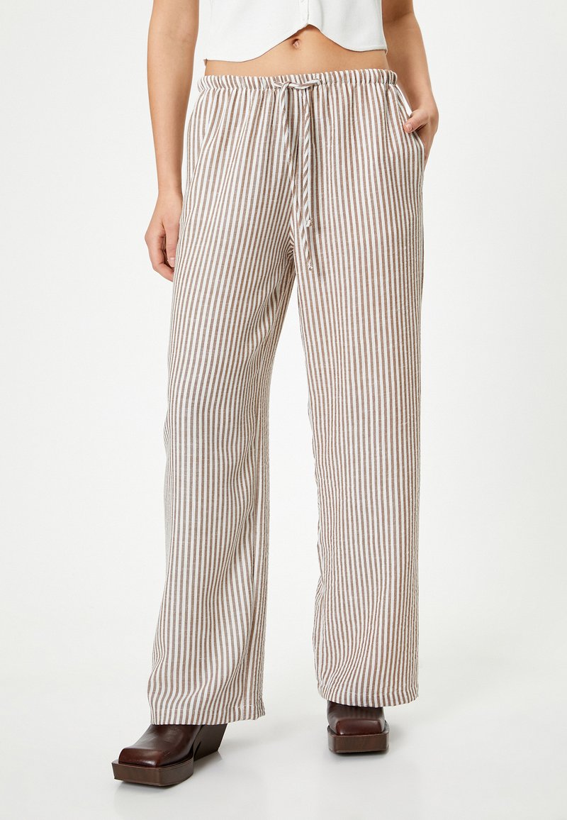 Pantalones palazzo ligeros a rayas en beige y marrón, con cintura elástica y cordón ajustable, y bolsillos laterales. Tejido texturizado.