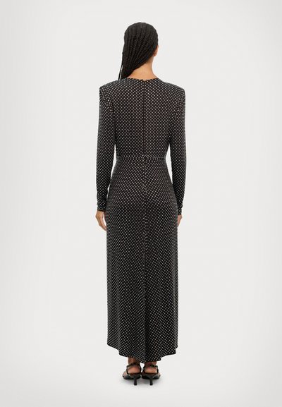 Zwart jurk met lange mouwen en witte stippen. Strak aansluitende taille, volle lengte met een rechte silhouet. Glad materiaal en een knoopdetail op de achterkant.