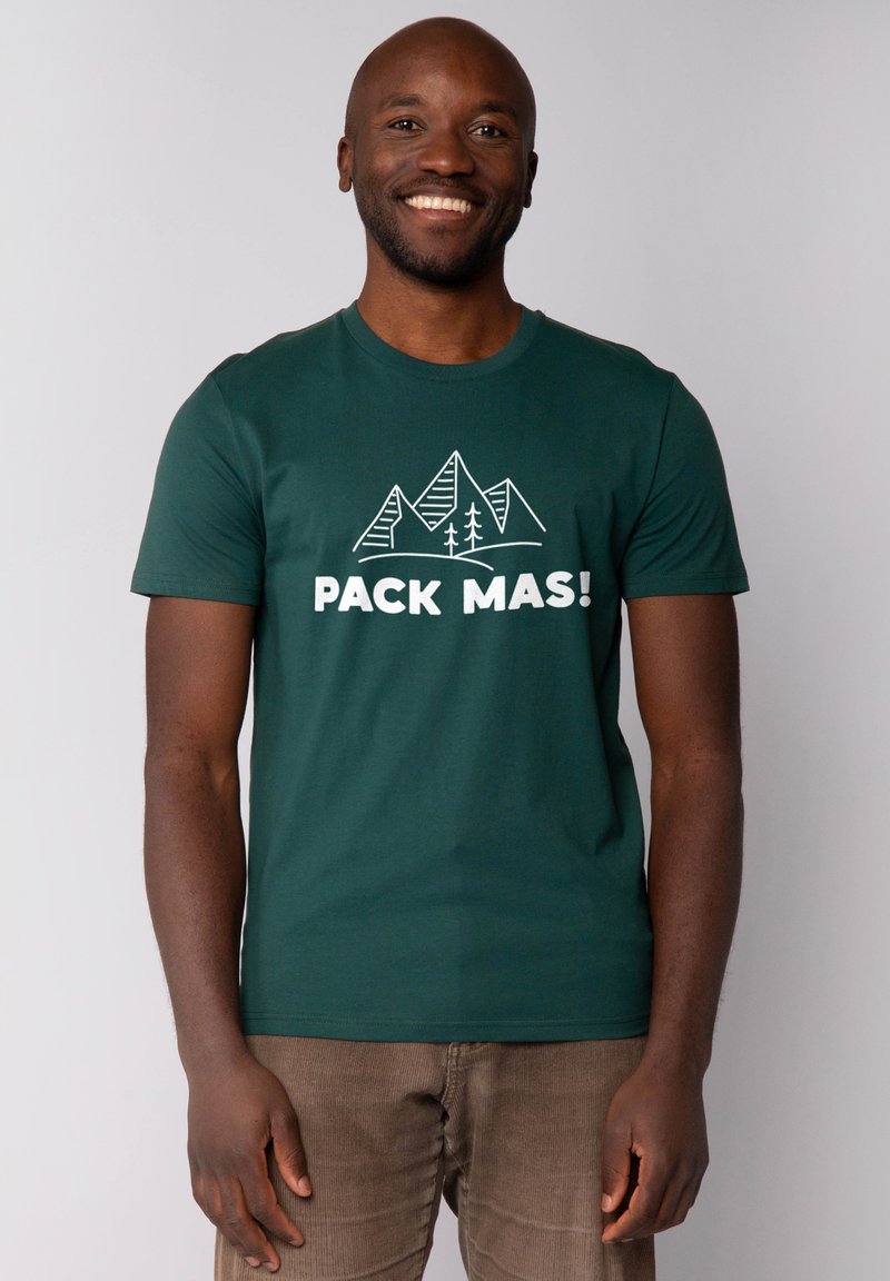 Grünes T-Shirt mit kurzen Ärmeln, das ein weißes Bergmotiv und den Text "PACK MAS!" in fetten Buchstaben zeigt. Hergestellt aus glattem Baumwollmaterial, mit Rundhalsausschnitt.