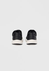 Sneakers nere con tomaia in mesh, dettagli in pelle liscia, intersuola bianca e suola esterna in gomma nera testurizzata. Dettaglio con cinturino a strappo visibile.