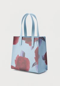Canvas tote bag with a light blue background, featuring a floral pattern of large red roses and green leaves. Sturdy handles.