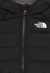 Veste isolante noire avec fermeture éclair à l'avant, équipée d'une capuche et d'un design matelassé. Logo blanc sur la poitrine gauche. Texture de tissu douce.