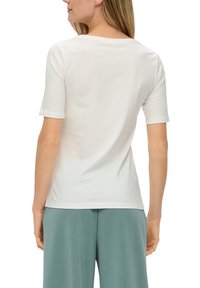 Lichtgrijs T-shirt met korte mouwen, gemaakt van zachte katoen. Heeft een ronde halslijn en een fitted ontwerp, met zichtbare stiksels op de schouders en mouwen.