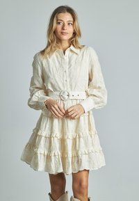 Helles Kleid mit floraler Stickerei, langen Ärmeln, gestuften Rüschen und einer taillierten Taille mit einem passenden Gürtel, der eine runde Schnalle hat.