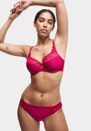 Fuchsia kanten bh en bijpassende slipjes met stippenpatroon, gegolfde randen en delicate strikjes. Zacht, doorschijnend materiaal zorgt voor een textuuroverzicht.