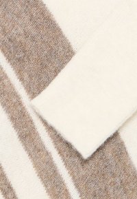 Maglione lavorato a maglia con righe alternate in crema e marrone chiaro, dotato di una texture morbida e dettagli sui polsini standard.