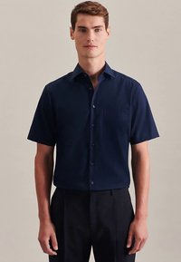 Donkerblauw shirt met korte mouwen gemaakt van gladde stof, met een button-down kraag, een borstzak en subtiele stikseldetails. Gestructureerde pasvorm.