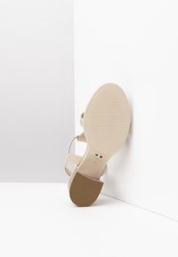 Beige high-heeled sandal with three adjustable straps, textured sole, and a brown heel. Label reads "NeroGiardini, Made in Italy, 37."